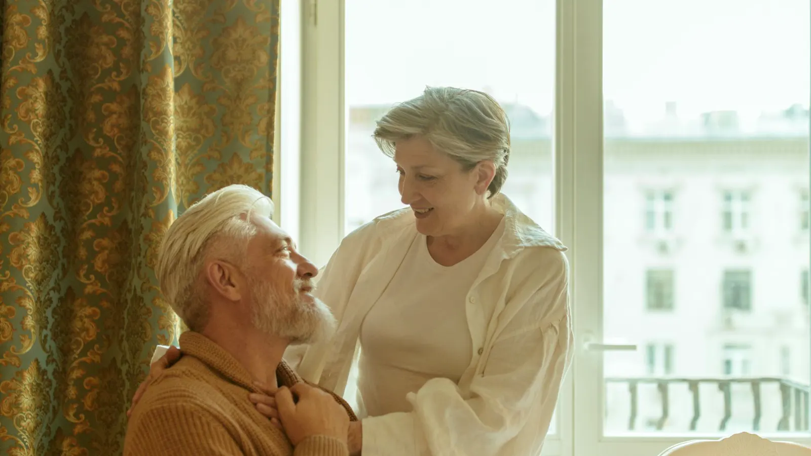 A carer talking with an older man by a window