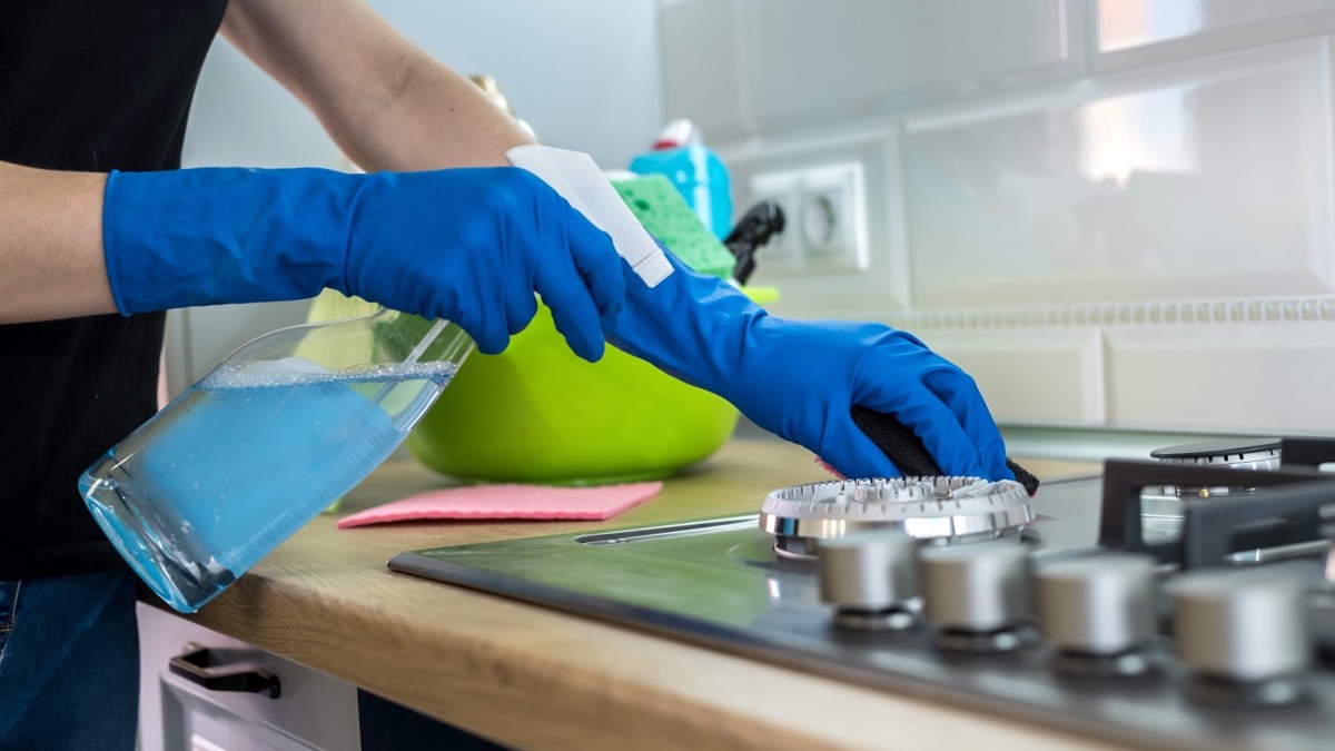 Gloved hands cleaning a kitchen surface with a cloth