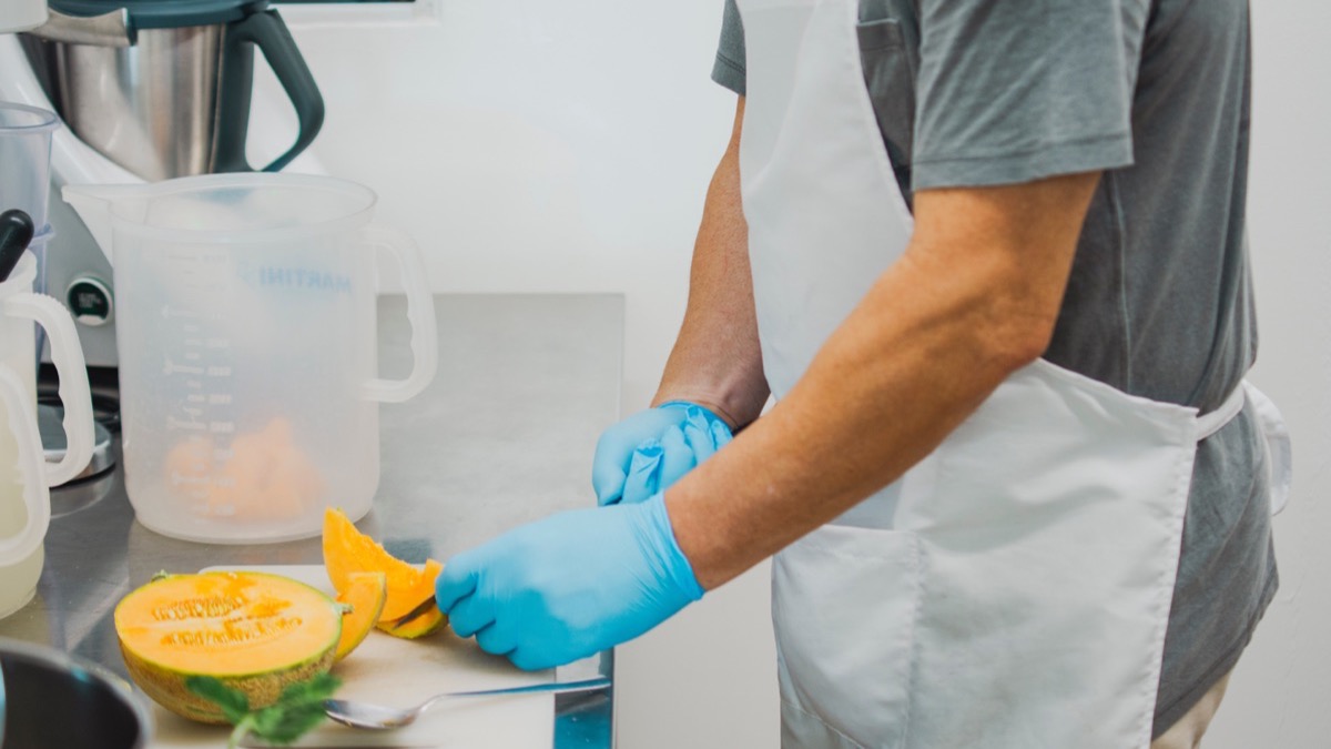 Food handler wearing blue gloves while preparing food