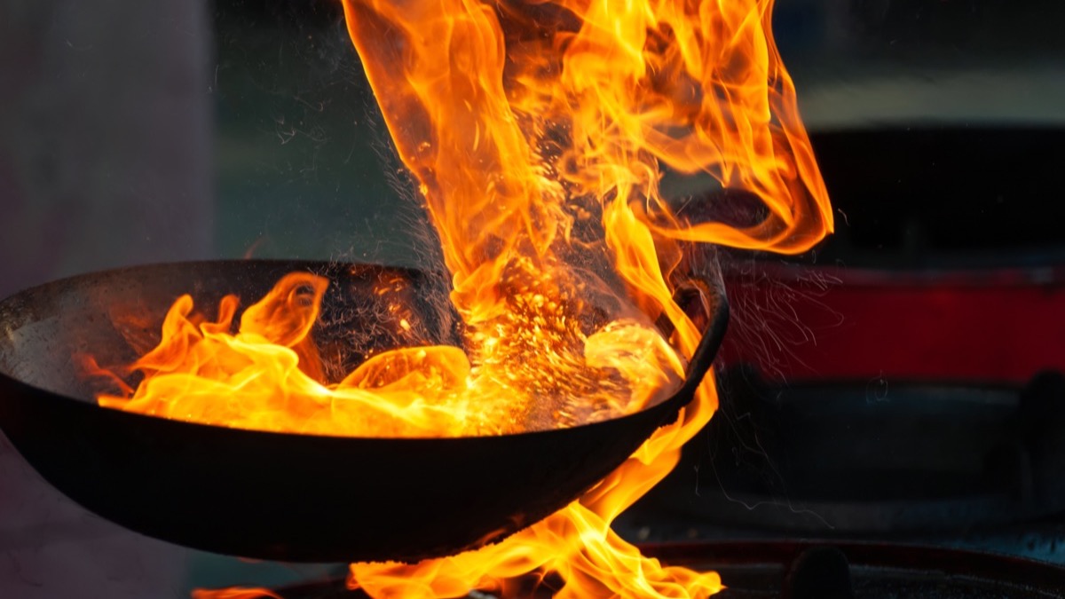 Flames rising from a pan on a commercial kitchen stove