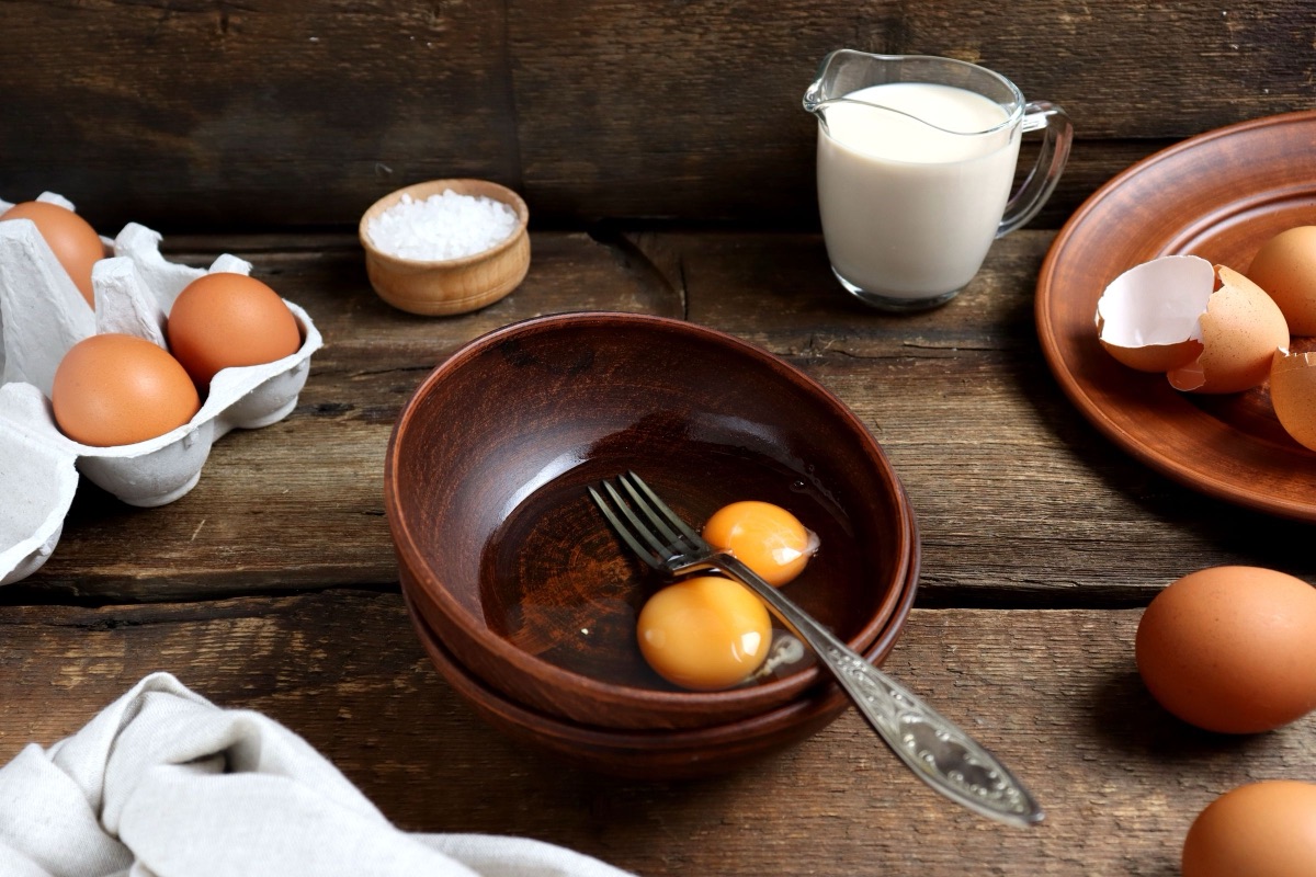 Eggs in a carton and a jug of milk on a rustic wooden table